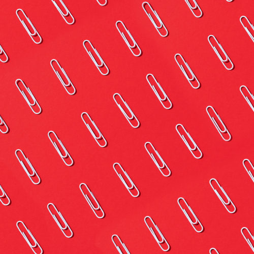 Pattern of white paper clips on red background. Back to school. Office, business, paperwork, education concept. Banner.
